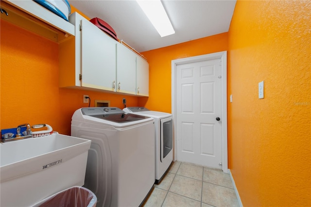 washroom featuring cabinets, light tile patterned floors, separate washer and dryer, and sink