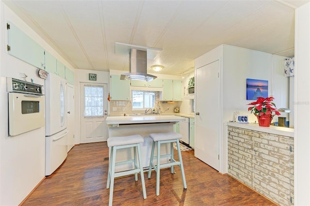 kitchen with white appliances, backsplash, dark wood-type flooring, and a breakfast bar area