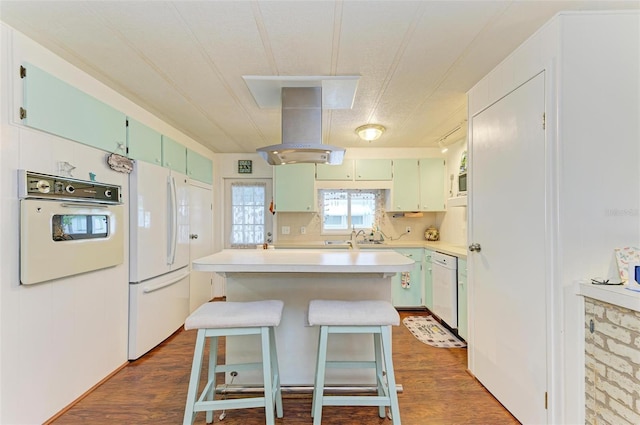 kitchen featuring a center island, white appliances, dark wood-type flooring, a kitchen breakfast bar, and island exhaust hood