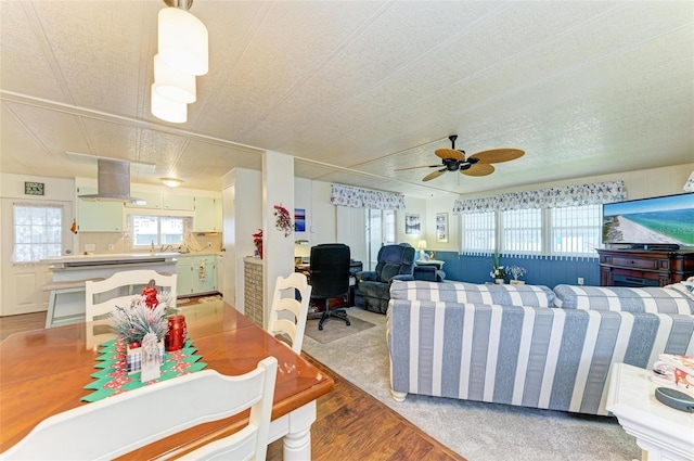 living room with ceiling fan, light wood-type flooring, and a textured ceiling