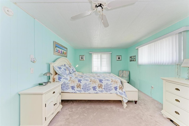 bedroom featuring ceiling fan, light colored carpet, and wooden walls