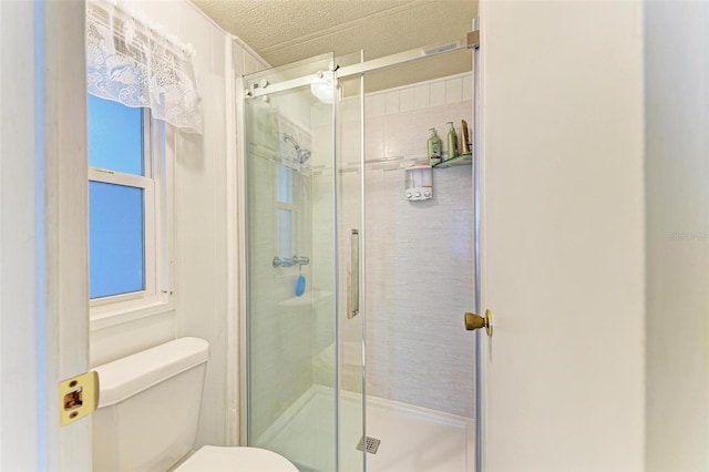 bathroom featuring a textured ceiling, toilet, and walk in shower