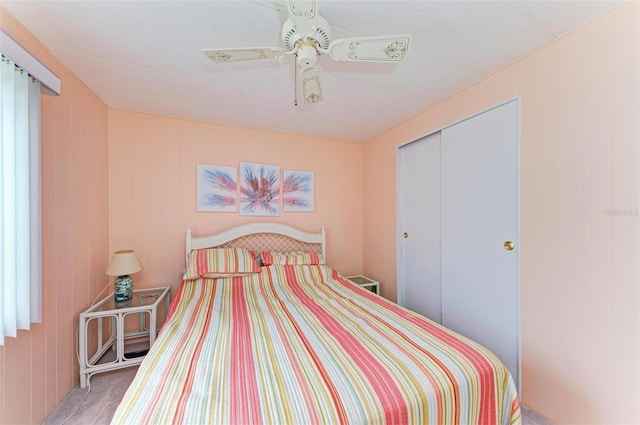 bedroom with ceiling fan, light colored carpet, and a closet