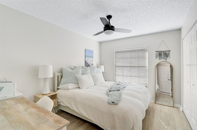 bedroom with ceiling fan, a closet, a textured ceiling, and light hardwood / wood-style flooring