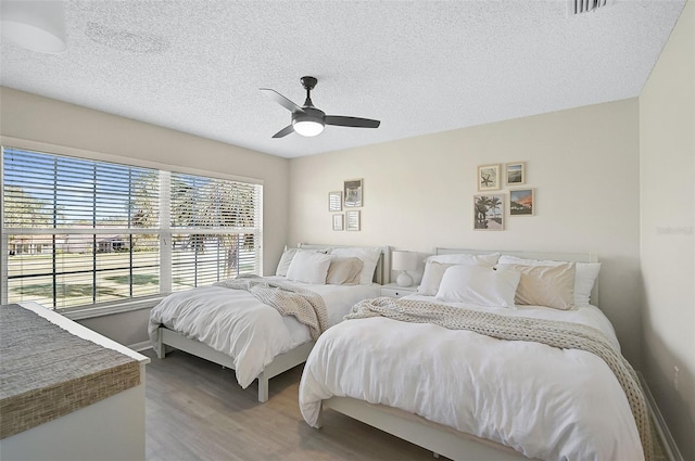 bedroom featuring ceiling fan, hardwood / wood-style floors, and a textured ceiling