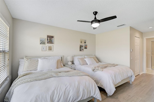 bedroom with hardwood / wood-style flooring, ceiling fan, a textured ceiling, and a closet