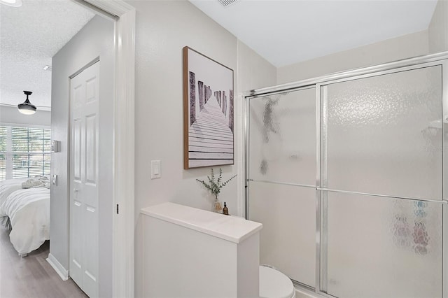 bathroom featuring an enclosed shower, wood-type flooring, a textured ceiling, and toilet