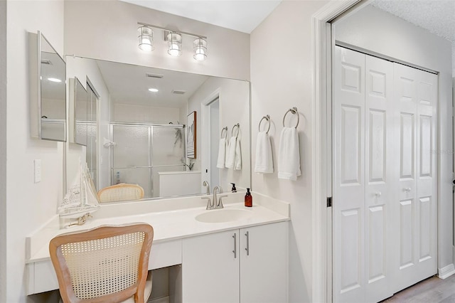 bathroom with hardwood / wood-style floors, vanity, and walk in shower