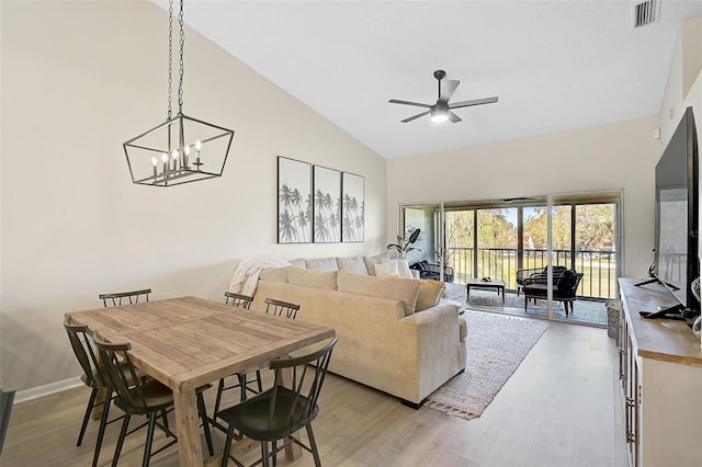 living room with light hardwood / wood-style flooring, high vaulted ceiling, and ceiling fan with notable chandelier