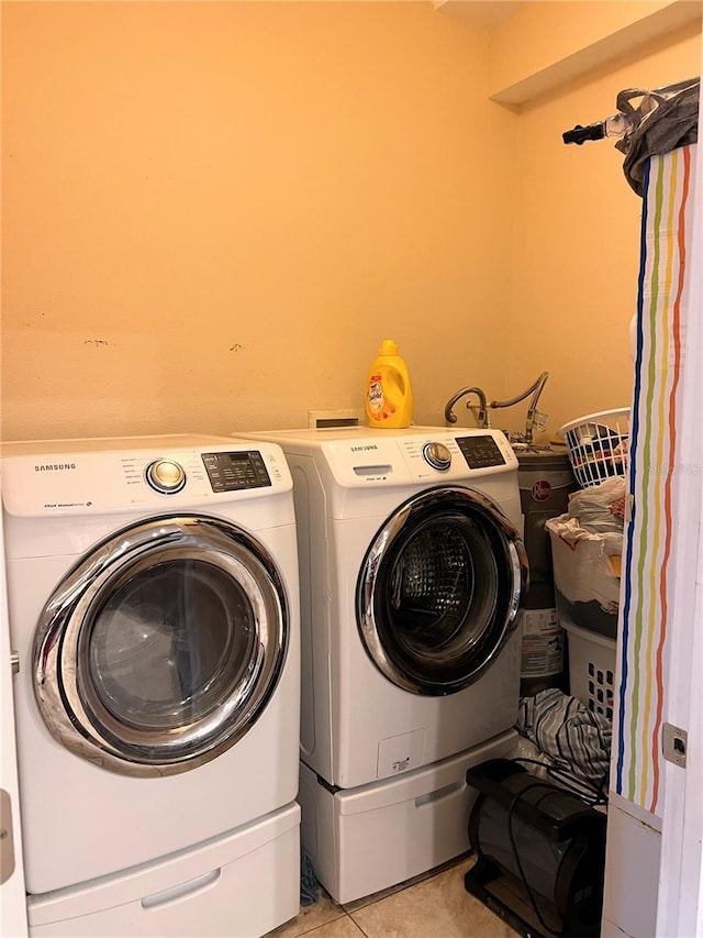 clothes washing area with washer and dryer and light tile patterned floors