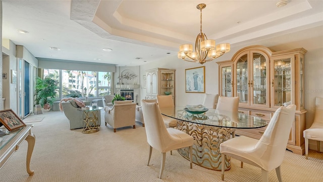 carpeted dining room with a notable chandelier and a raised ceiling