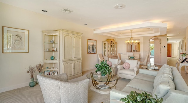 living room featuring a notable chandelier, light carpet, and a tray ceiling