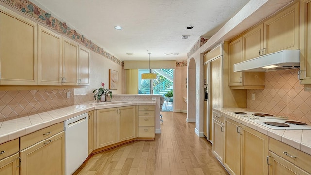 kitchen with white appliances, sink, decorative light fixtures, light hardwood / wood-style flooring, and tile counters