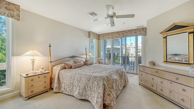 carpeted bedroom with multiple windows, ceiling fan, and access to exterior