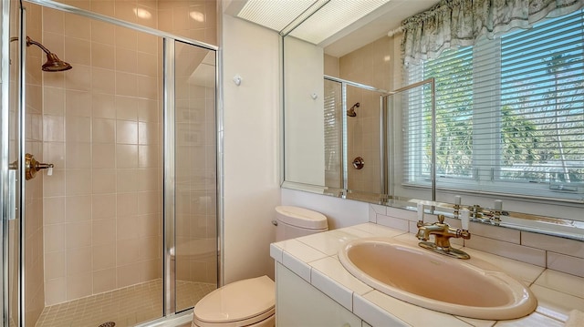 bathroom featuring vanity, a shower with shower door, and toilet