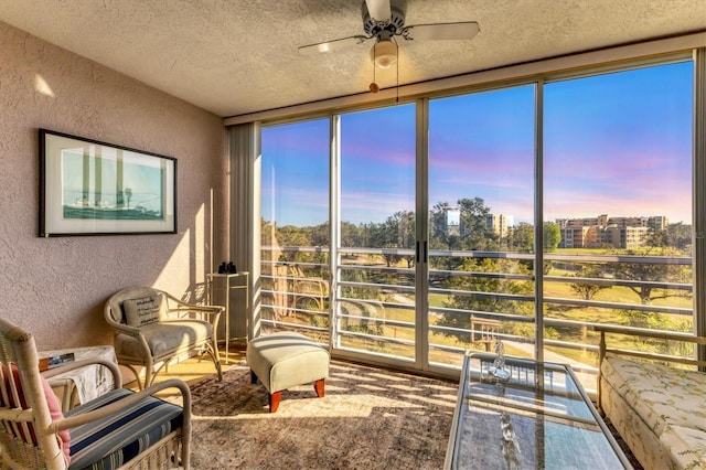 living area with ceiling fan, a healthy amount of sunlight, a textured ceiling, and a wall of windows