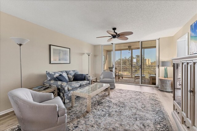 living room featuring ceiling fan, floor to ceiling windows, light wood-type flooring, and a textured ceiling