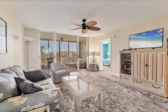 living room featuring floor to ceiling windows, ceiling fan, light hardwood / wood-style flooring, and a textured ceiling