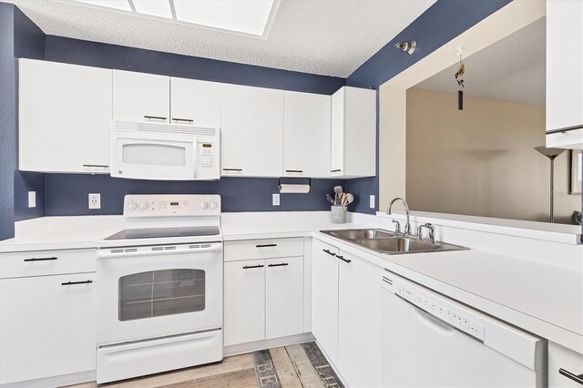 kitchen featuring light wood-type flooring, white appliances, a textured ceiling, sink, and white cabinets