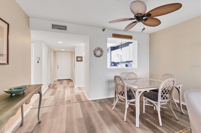 dining area featuring ceiling fan, light hardwood / wood-style floors, and a textured ceiling