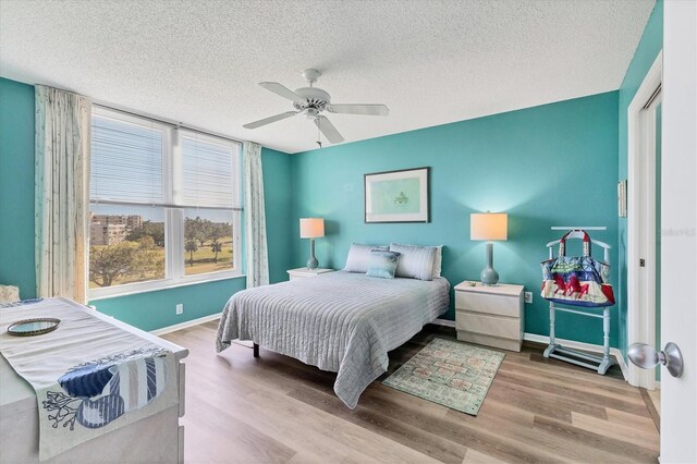 bedroom with ceiling fan, wood-type flooring, and a textured ceiling