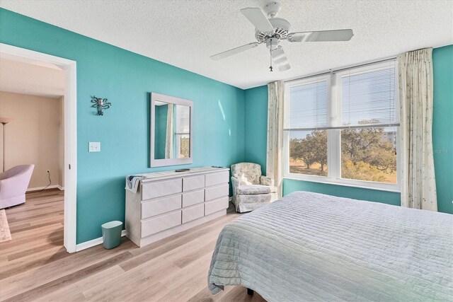 bedroom with ceiling fan, light hardwood / wood-style floors, and a textured ceiling