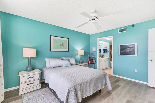 bedroom featuring a textured ceiling, ceiling fan, ensuite bathroom, and light hardwood / wood-style flooring