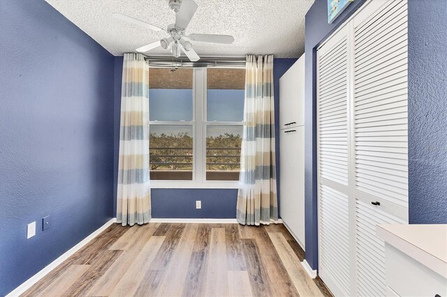 unfurnished room featuring ceiling fan, wood-type flooring, and a textured ceiling