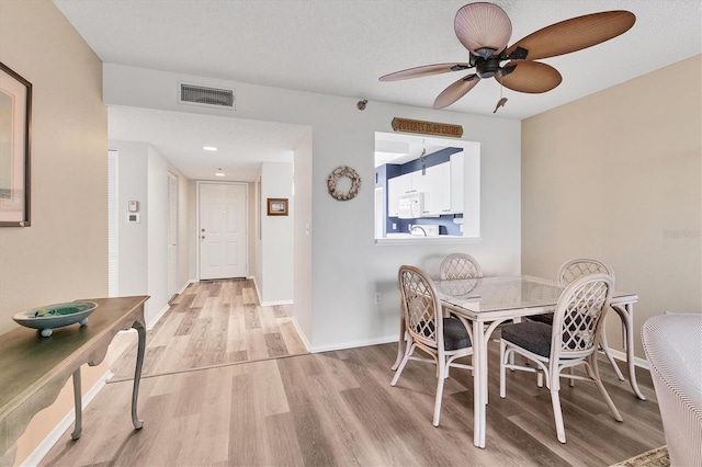 dining space featuring baseboards, ceiling fan, light wood finished floors, and visible vents