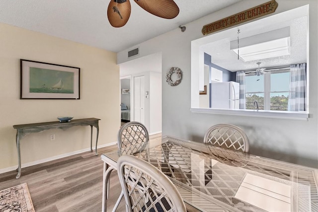 dining space featuring a ceiling fan, baseboards, visible vents, and wood finished floors