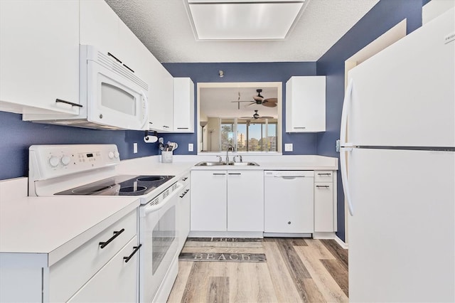 kitchen featuring white appliances, a sink, light wood-style floors, light countertops, and white cabinets
