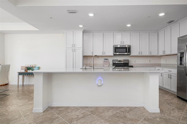 kitchen with sink, white cabinetry, stainless steel appliances, and a kitchen island with sink