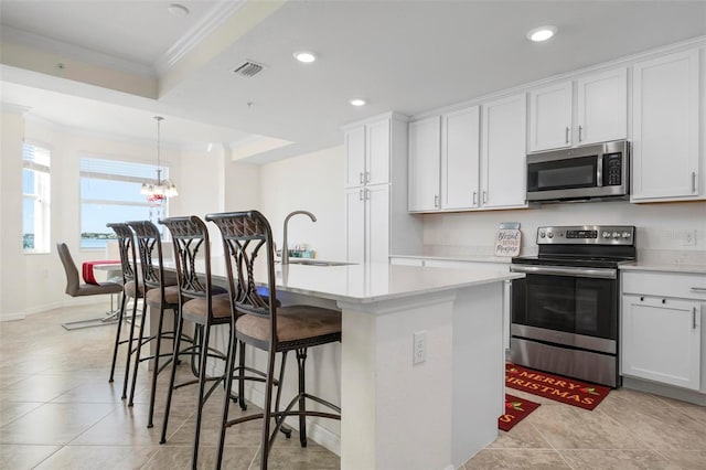 kitchen featuring white cabinets, appliances with stainless steel finishes, and a center island with sink