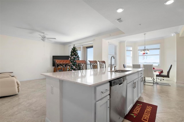 kitchen with a healthy amount of sunlight, hanging light fixtures, stainless steel dishwasher, and a center island with sink