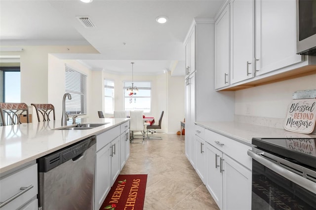 kitchen with a healthy amount of sunlight, white cabinetry, stainless steel appliances, and ornamental molding