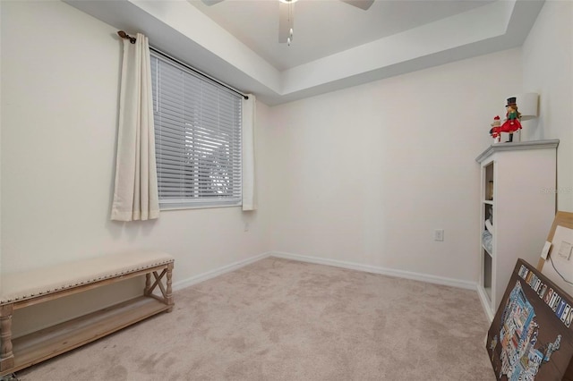 spare room featuring light carpet, a tray ceiling, and ceiling fan