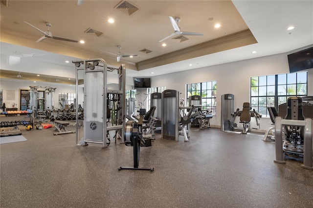 workout area with a raised ceiling, ceiling fan, and crown molding