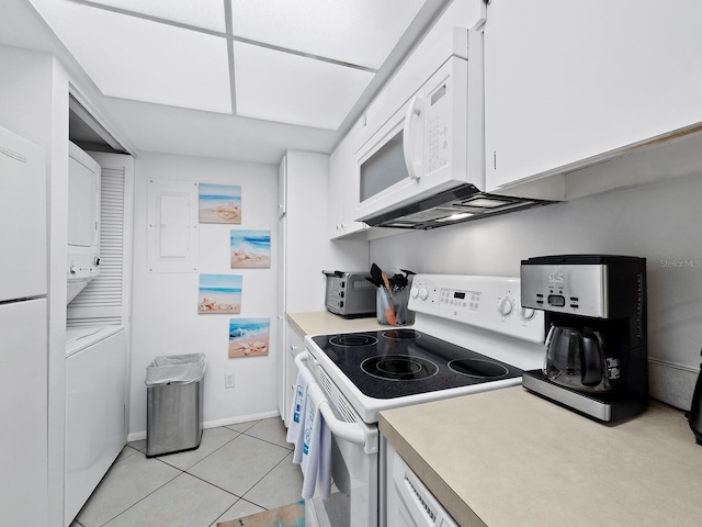 kitchen featuring stacked washer and dryer, white cabinets, white appliances, and light tile patterned floors