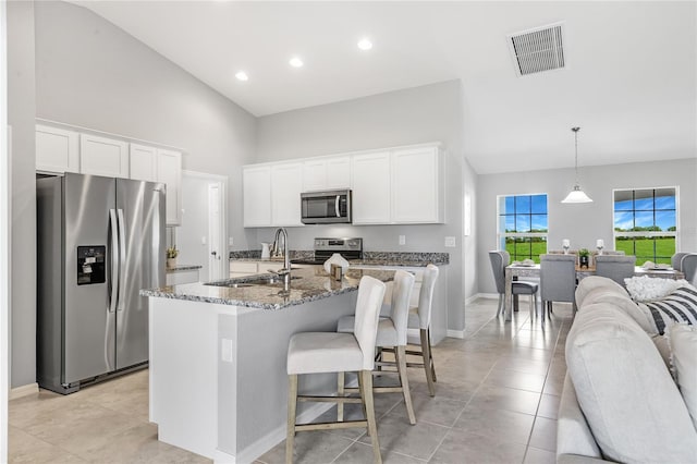 kitchen with stainless steel appliances, a kitchen island with sink, sink, decorative light fixtures, and white cabinetry