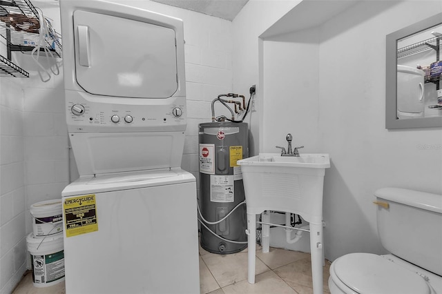 bathroom featuring electric water heater, stacked washer and clothes dryer, tile patterned floors, sink, and toilet