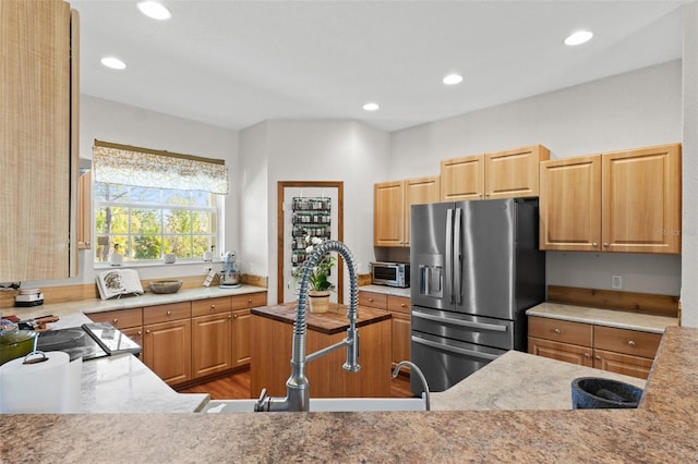 kitchen with stainless steel fridge with ice dispenser, light wood-type flooring, light brown cabinetry, and sink