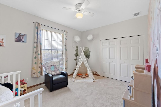 carpeted bedroom featuring ceiling fan, a closet, and a nursery area