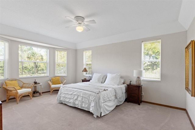 bedroom featuring ceiling fan, light carpet, and multiple windows