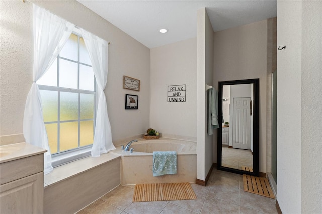 bathroom with tile patterned floors, a bathing tub, and vanity