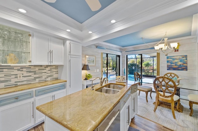 kitchen featuring an island with sink, white cabinetry, stainless steel dishwasher, and sink