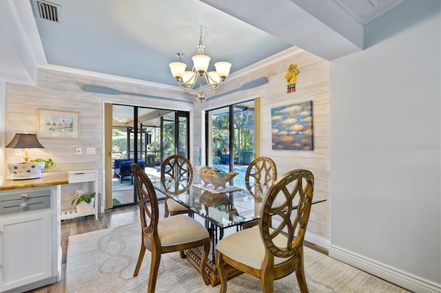 dining area featuring wooden walls, hardwood / wood-style flooring, and a notable chandelier