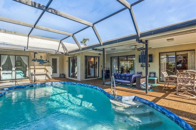 view of pool with glass enclosure, ceiling fan, and a patio area