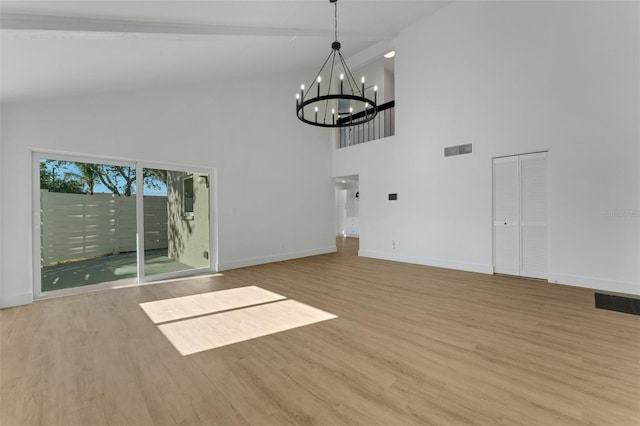 unfurnished living room with beamed ceiling, light wood-type flooring, high vaulted ceiling, and a notable chandelier