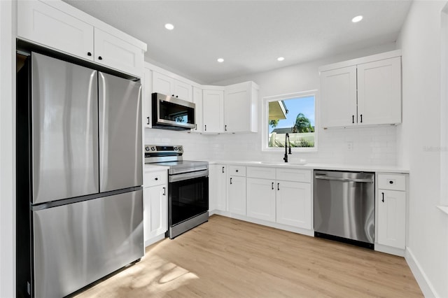 kitchen with sink, white cabinets, light hardwood / wood-style flooring, and appliances with stainless steel finishes