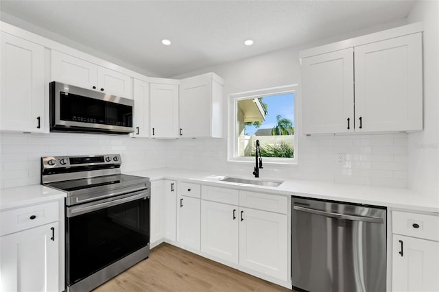 kitchen with tasteful backsplash, sink, white cabinets, and stainless steel appliances